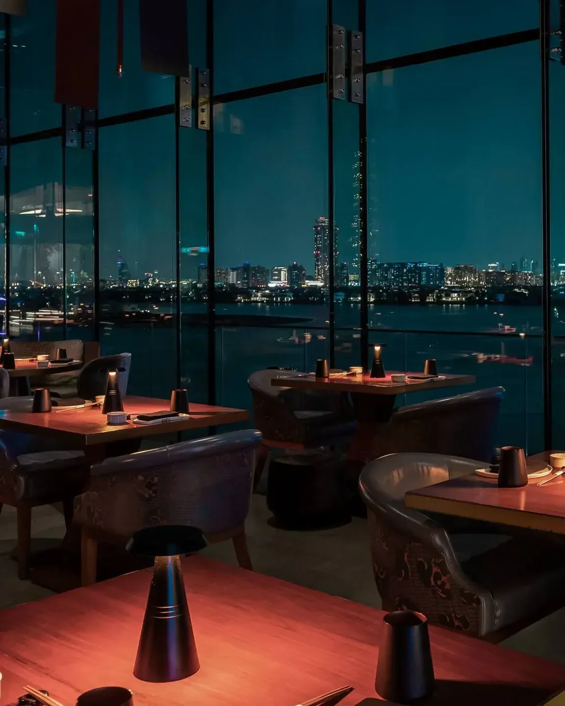 Night view of Akira Back Dubai restaurant interior with city lights in background.