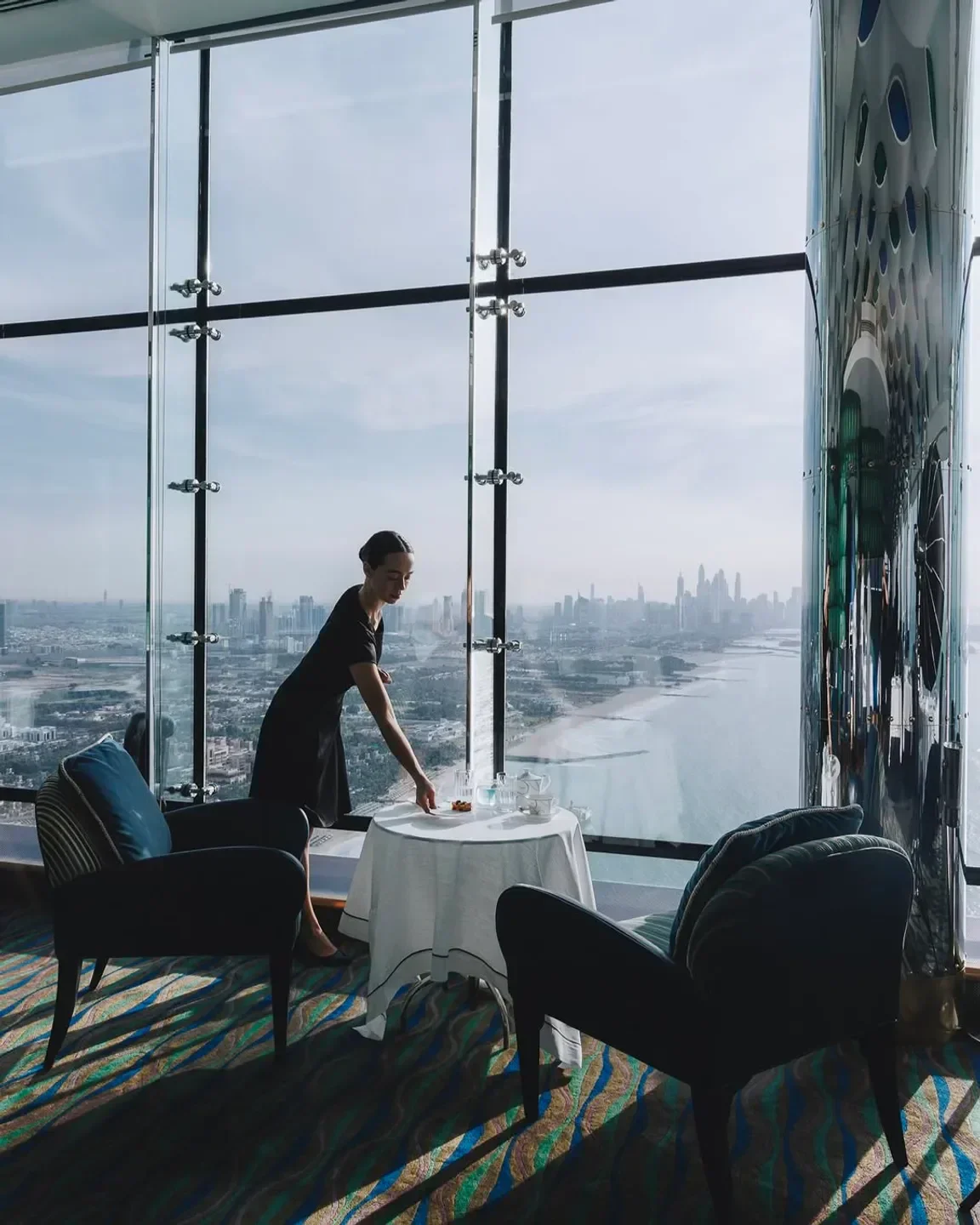 Al Muntaha Dubai: Fine dining with stunning city views, a server arranging tea service.