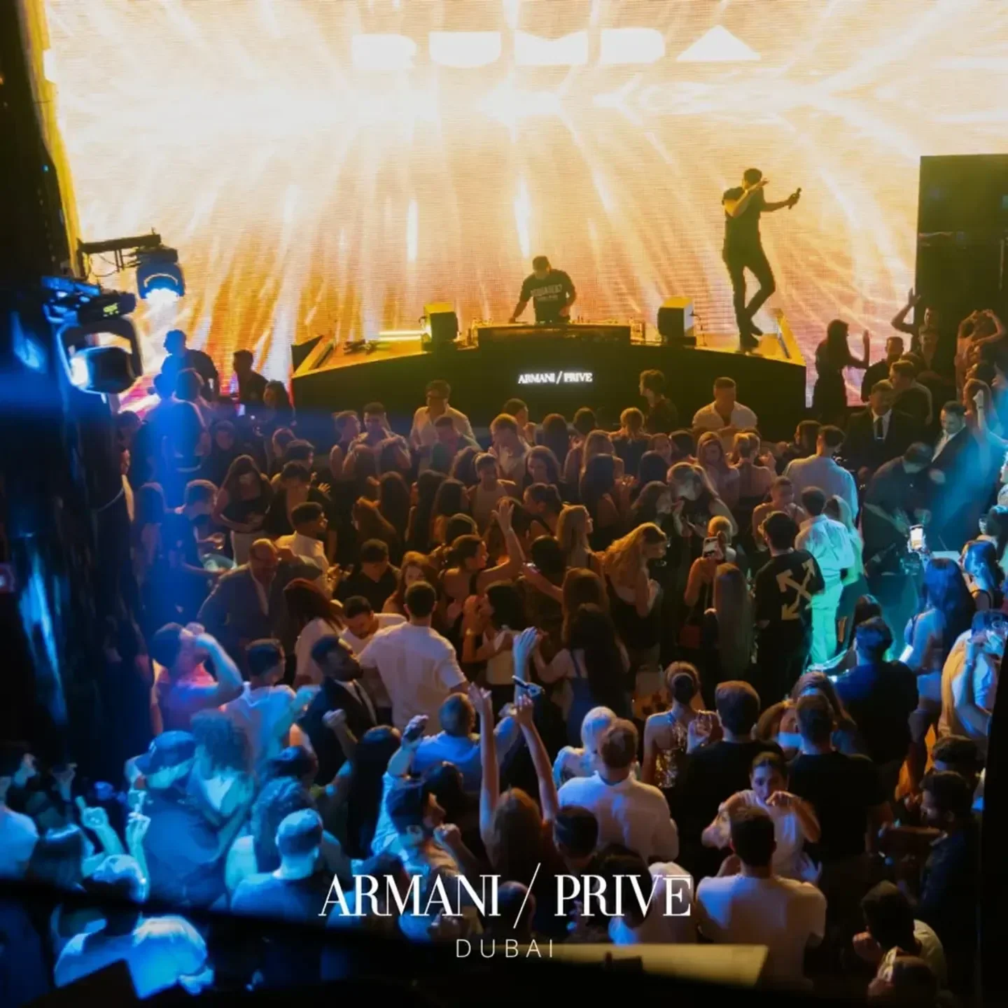 Energetic crowd at Armani/Prive nightclub in Dubai with DJ and stage lights.