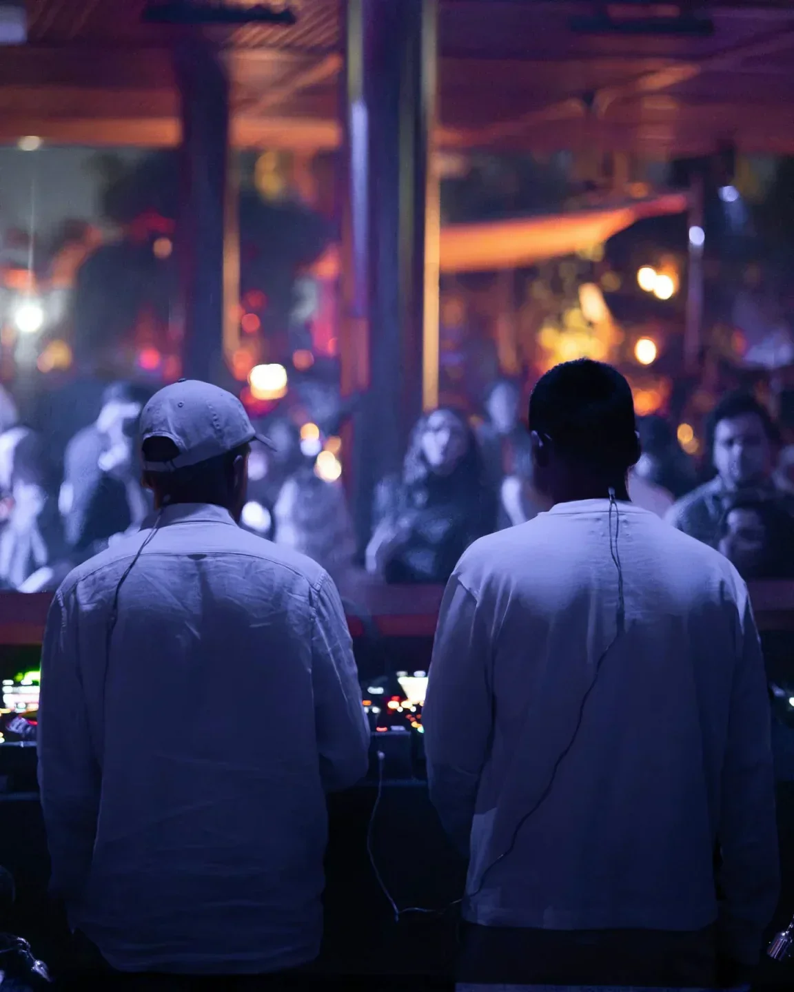 DJs performing at a lively party in Baoli Beach Dubai, with blurred crowd background.