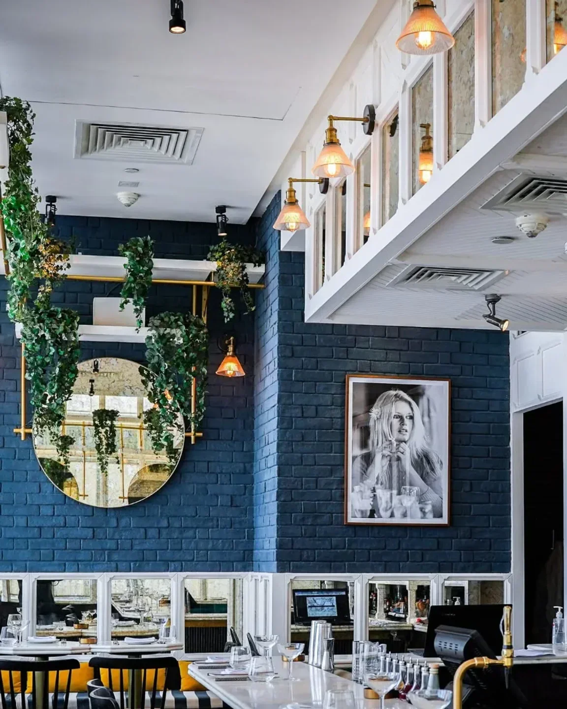Stylish interior of BB Social Dining in Dubai featuring a mirror, brick wall, and artwork.
