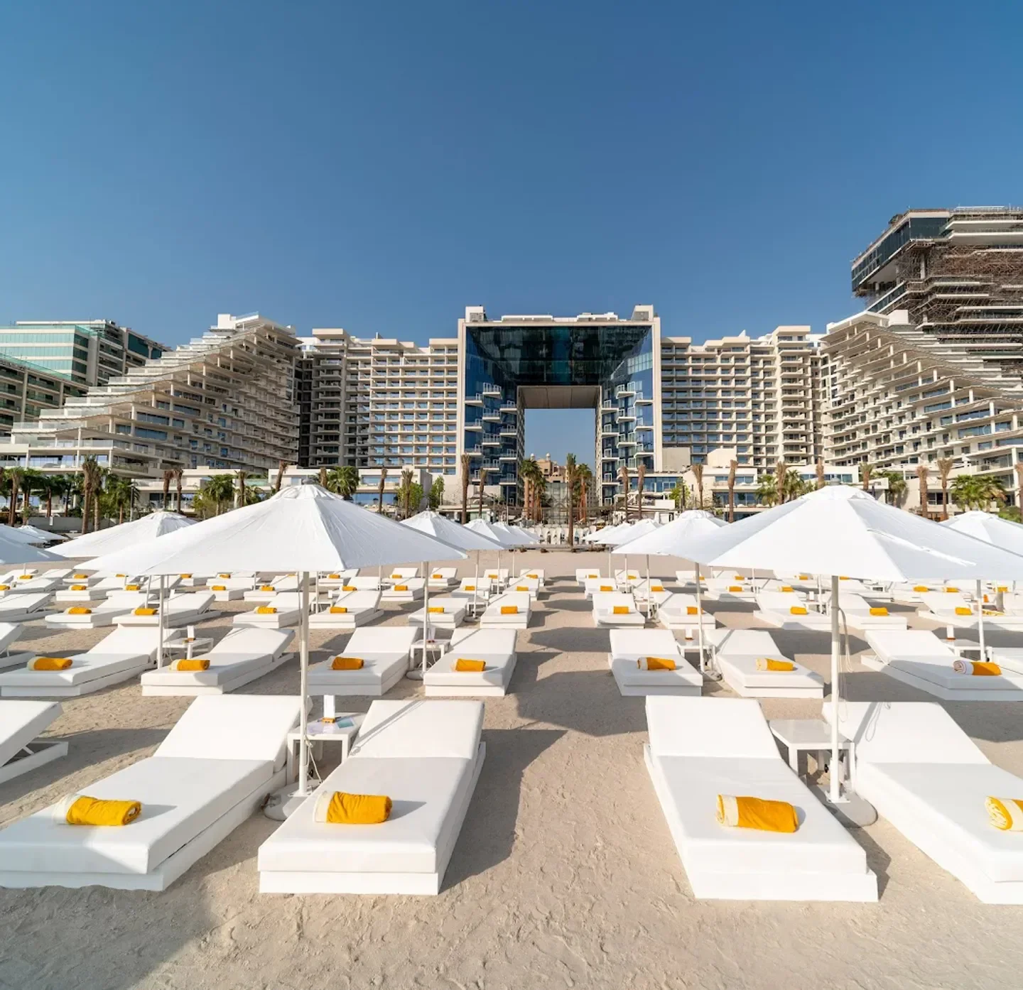 Beach by FIVE Dubai: Luxurious beach club with white sunbeds and umbrellas under blue skies.