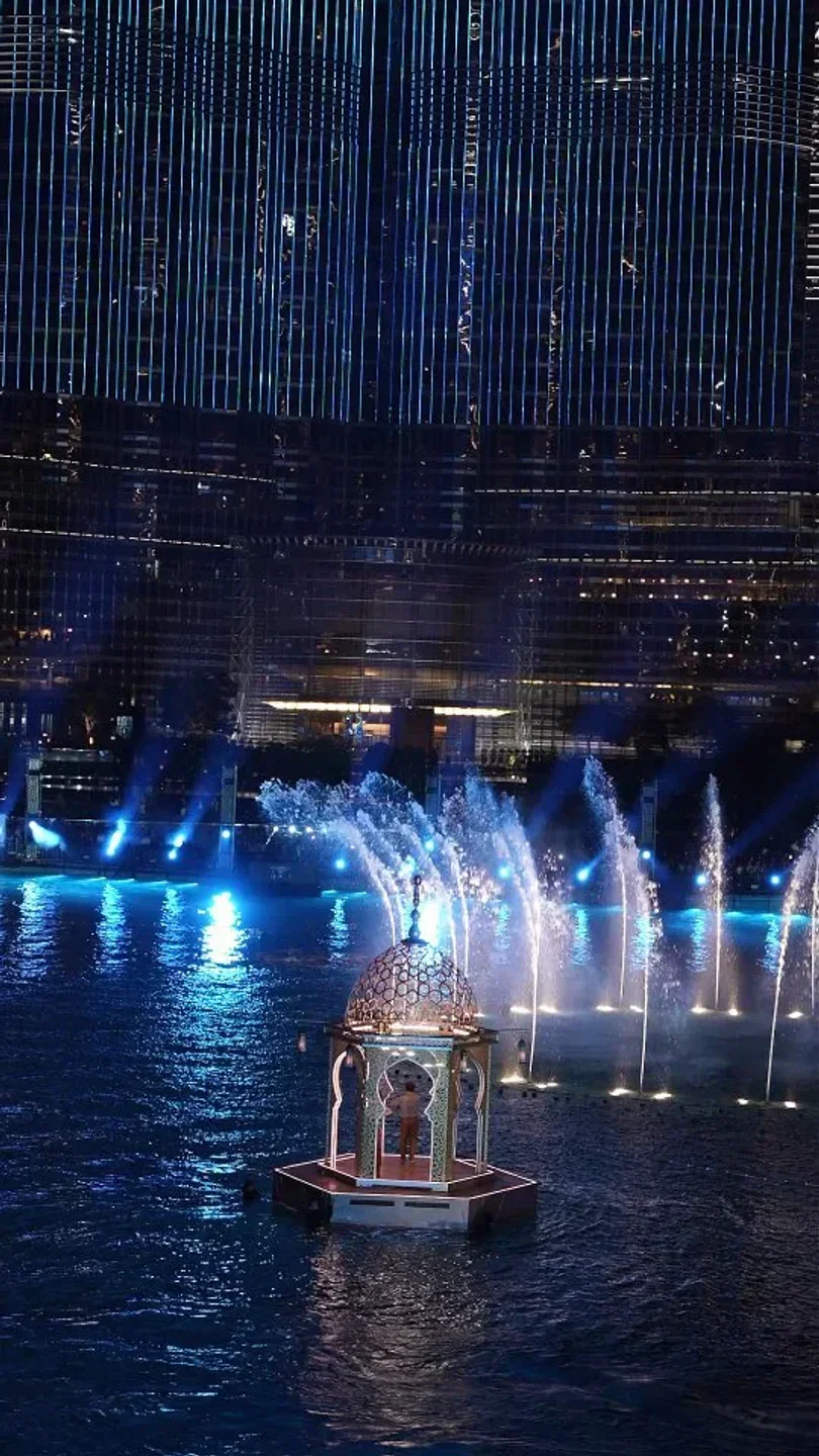 Bice Mare Dubai: Water fountain display with a floating gazebo at night, city lights.