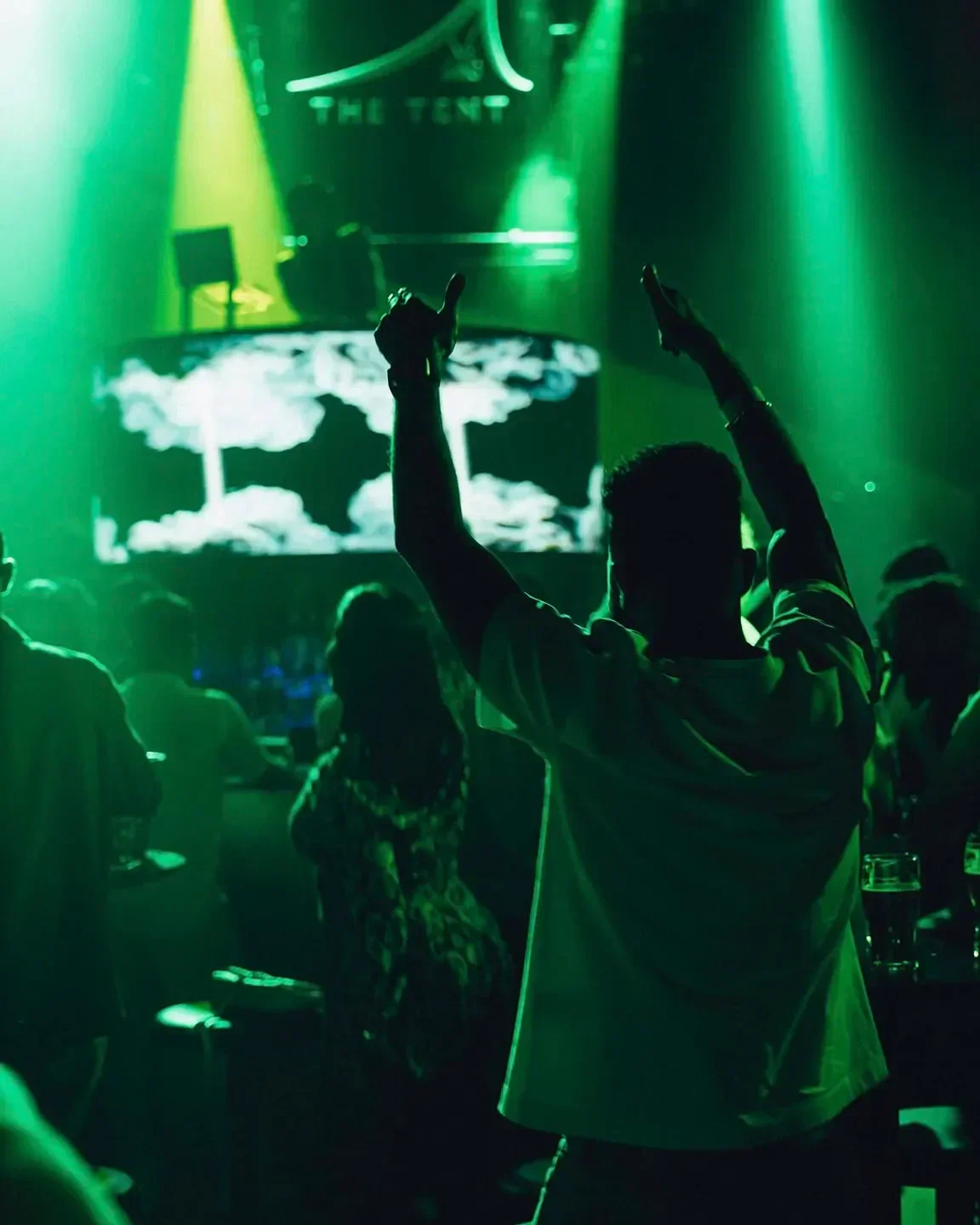 Energetic crowd enjoying the nightlife at Bla Bla restaurant in Dubai, arms raised.