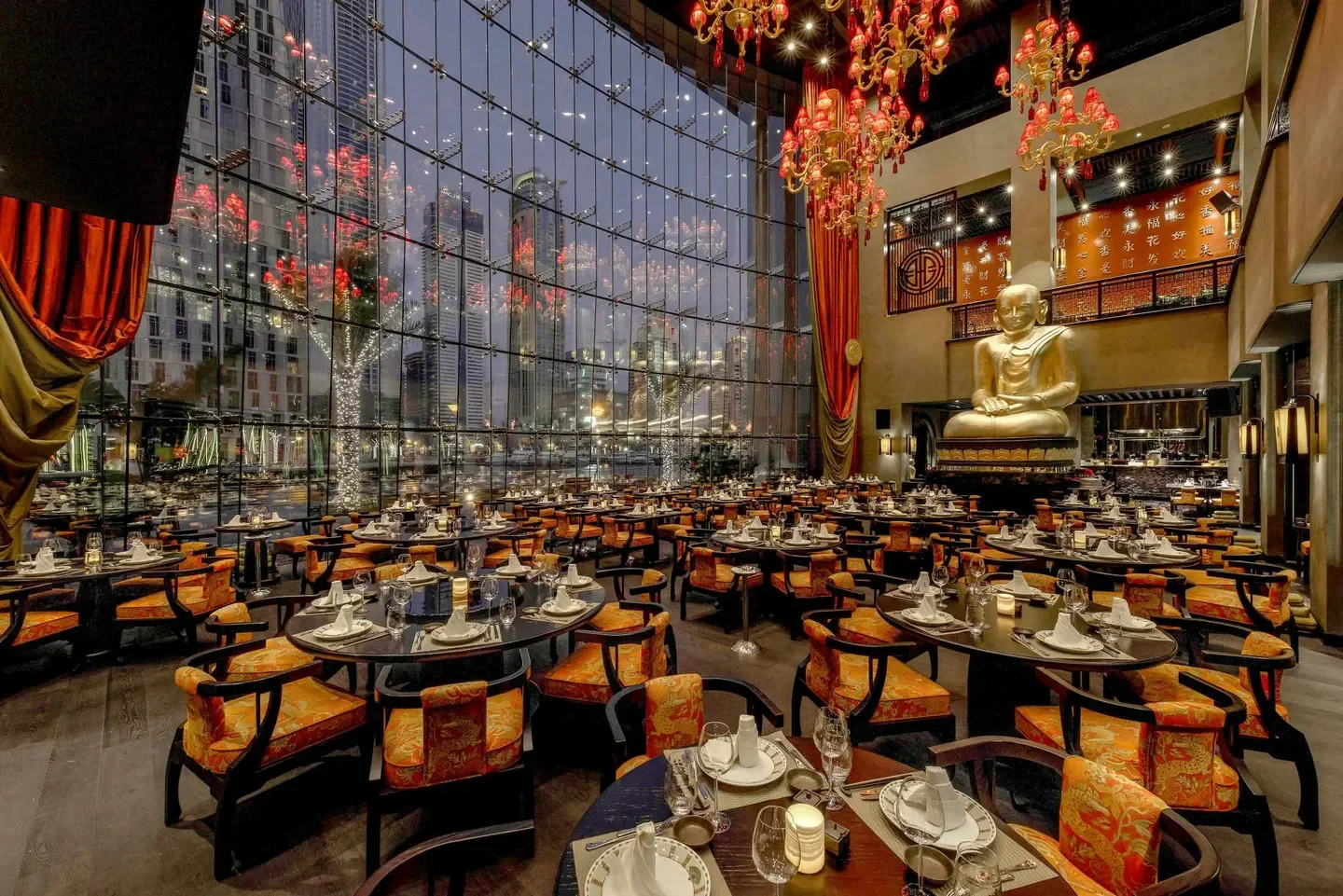 Interior of Buddha Bar Dubai with golden Buddha statue and city views at night.
