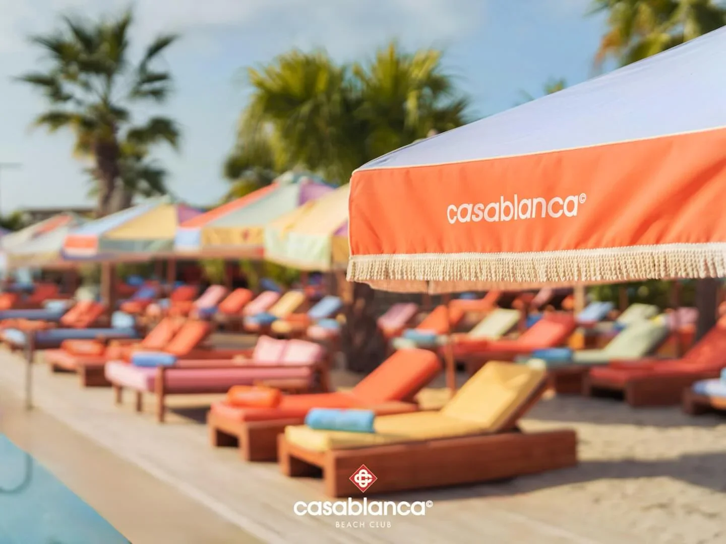 Casablanca Beach Club ambiance with colorful umbrellas and lounge chairs set up on the sand overlooking the city.