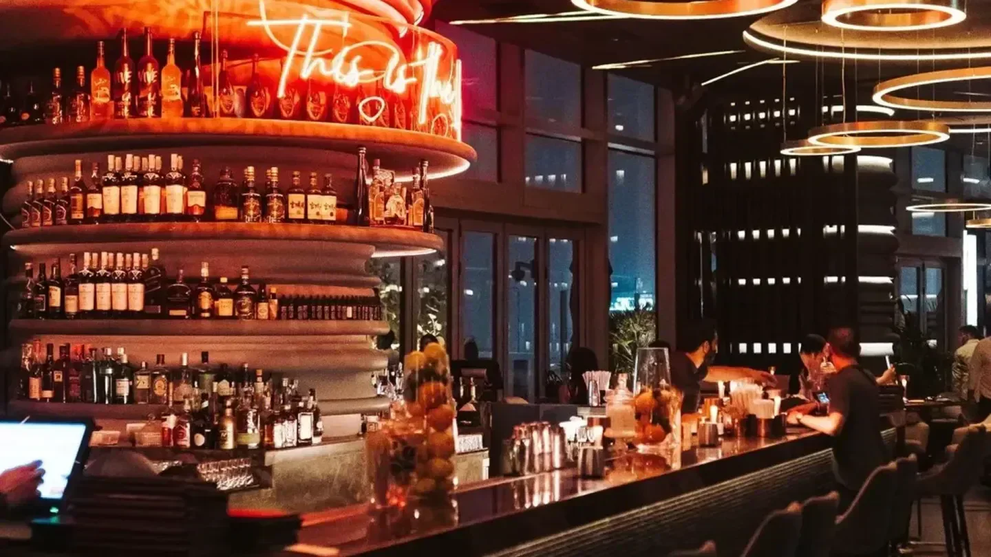 Interior of CE LA VI Dubai rooftop bar with neon sign and stocked shelves.