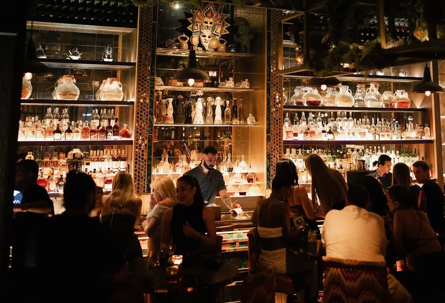 Stylish bar scene at COYA Dubai, showcasing a well-stocked bar and bustling atmosphere.
