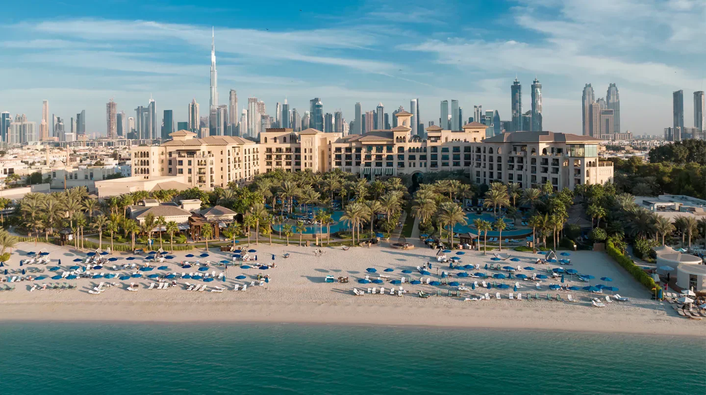 Beach view of Four Seasons Resort Dubai at Jumeirah Beach with Dubai skyline in the background.