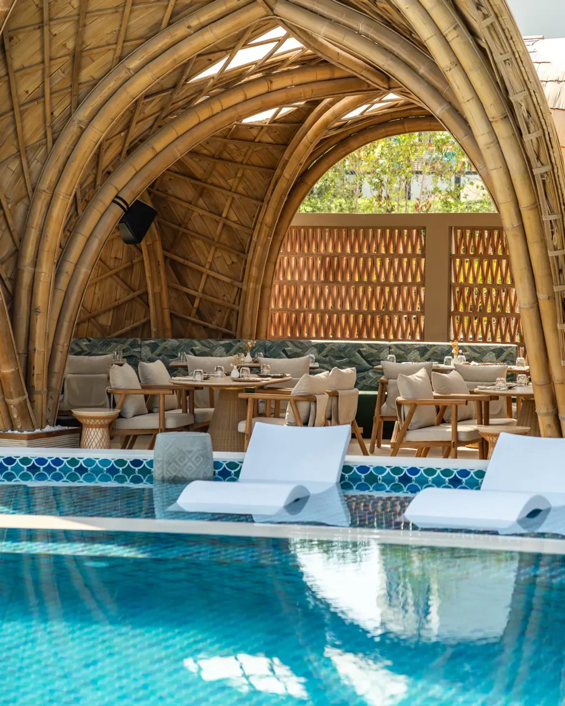 Kaimana Dubai: restaurant with pool, bamboo structure, and relaxing lounge chairs.