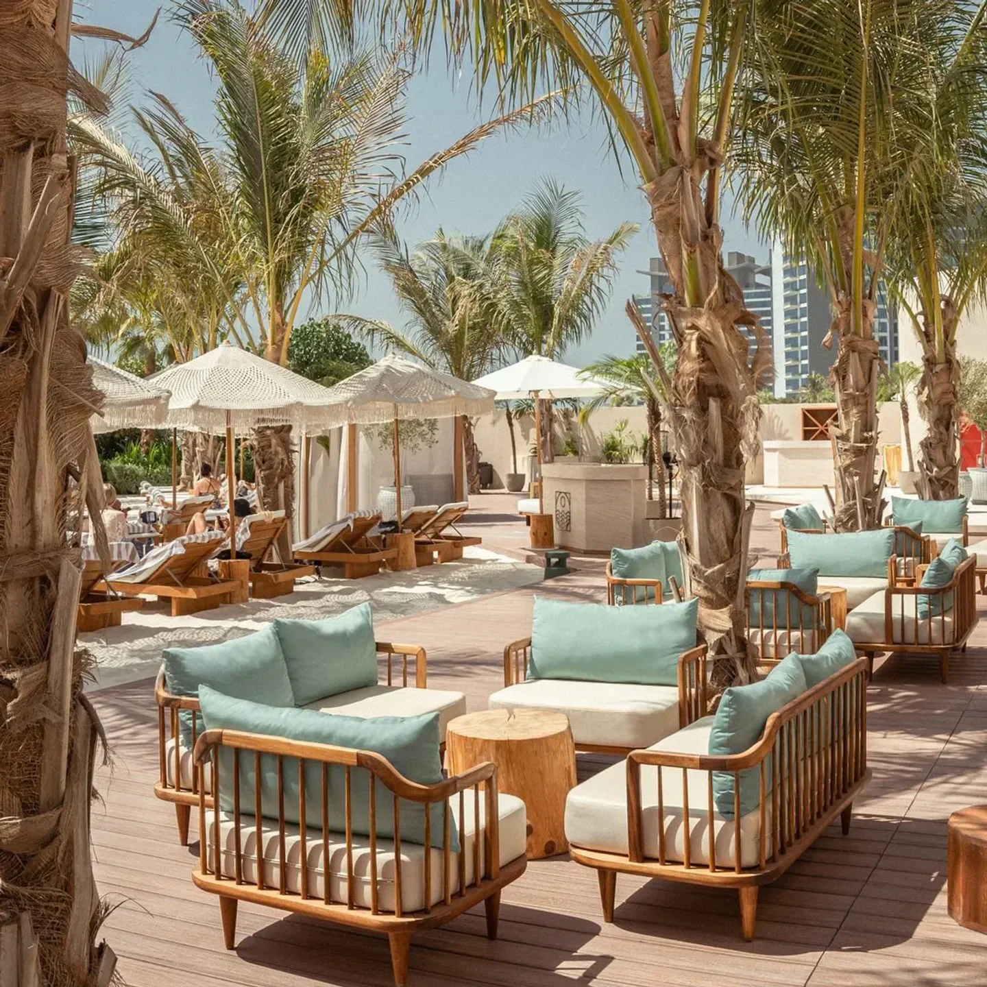 Kyma Beach in Dubai: inviting lounge seating under palm trees at the beach club.