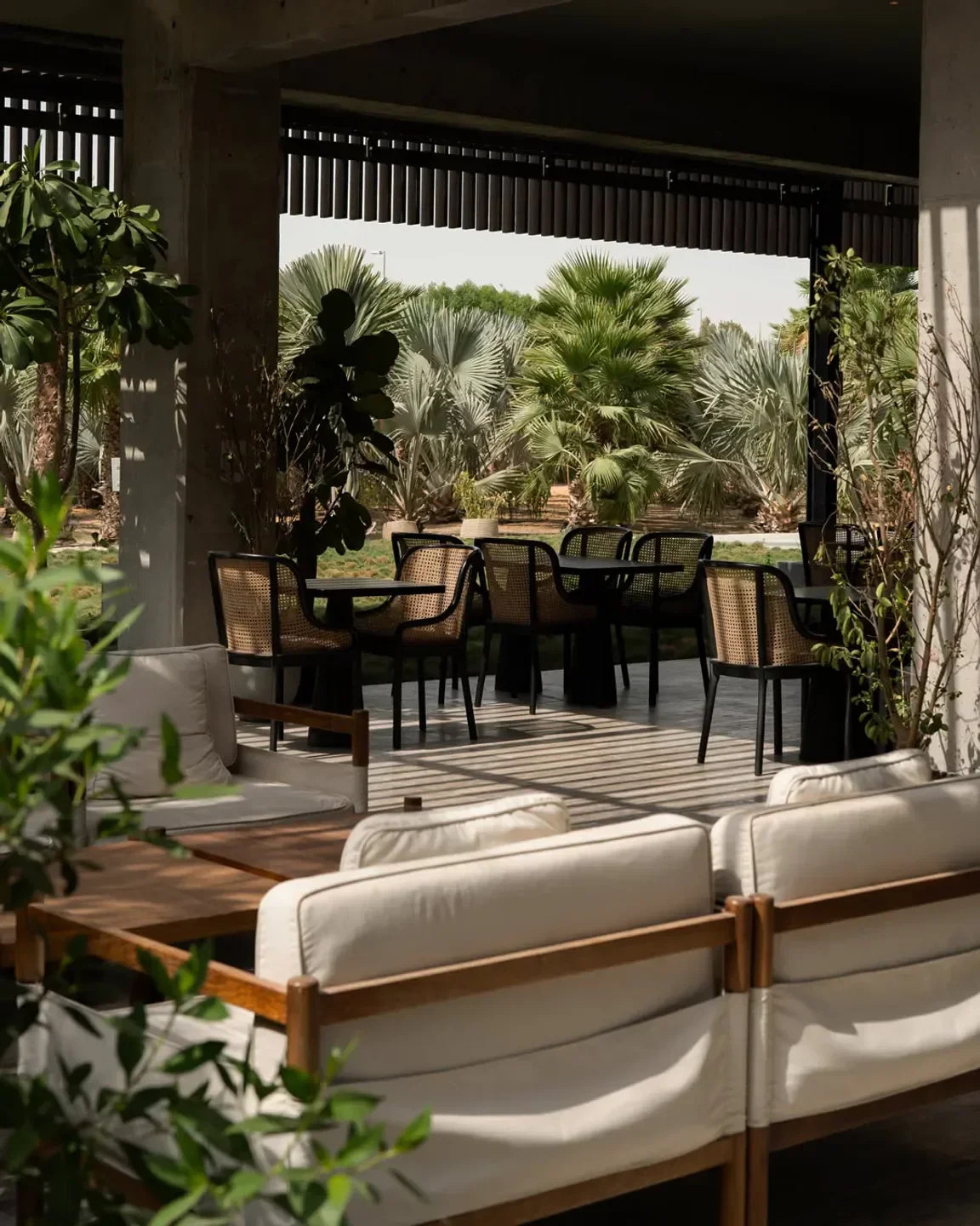 Outdoor seating at LOWE restaurant in Dubai, surrounded by lush greenery and palm trees.