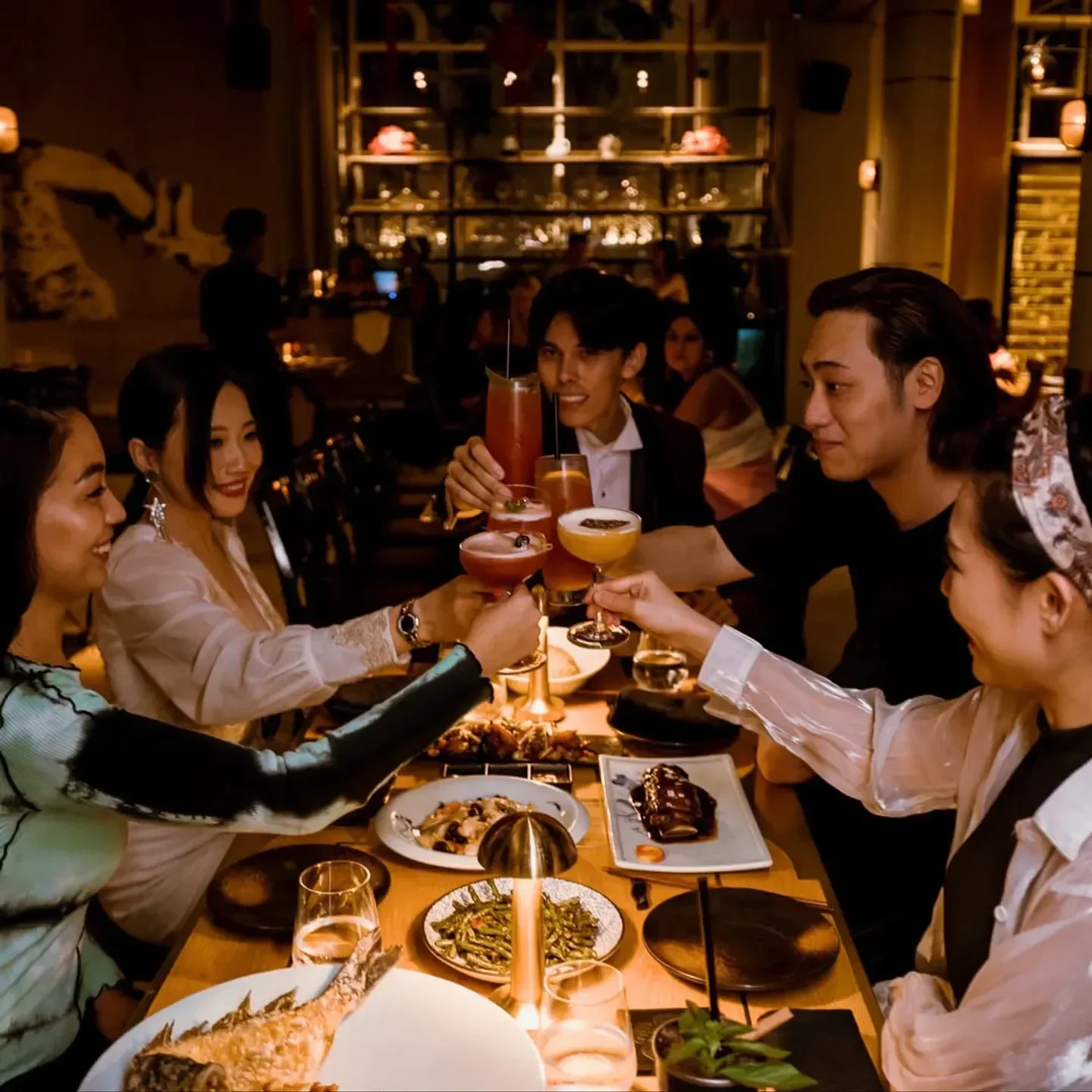 Friends toasting cocktails at Maiden Shanghai Dubai, enjoying a delightful dining experience.