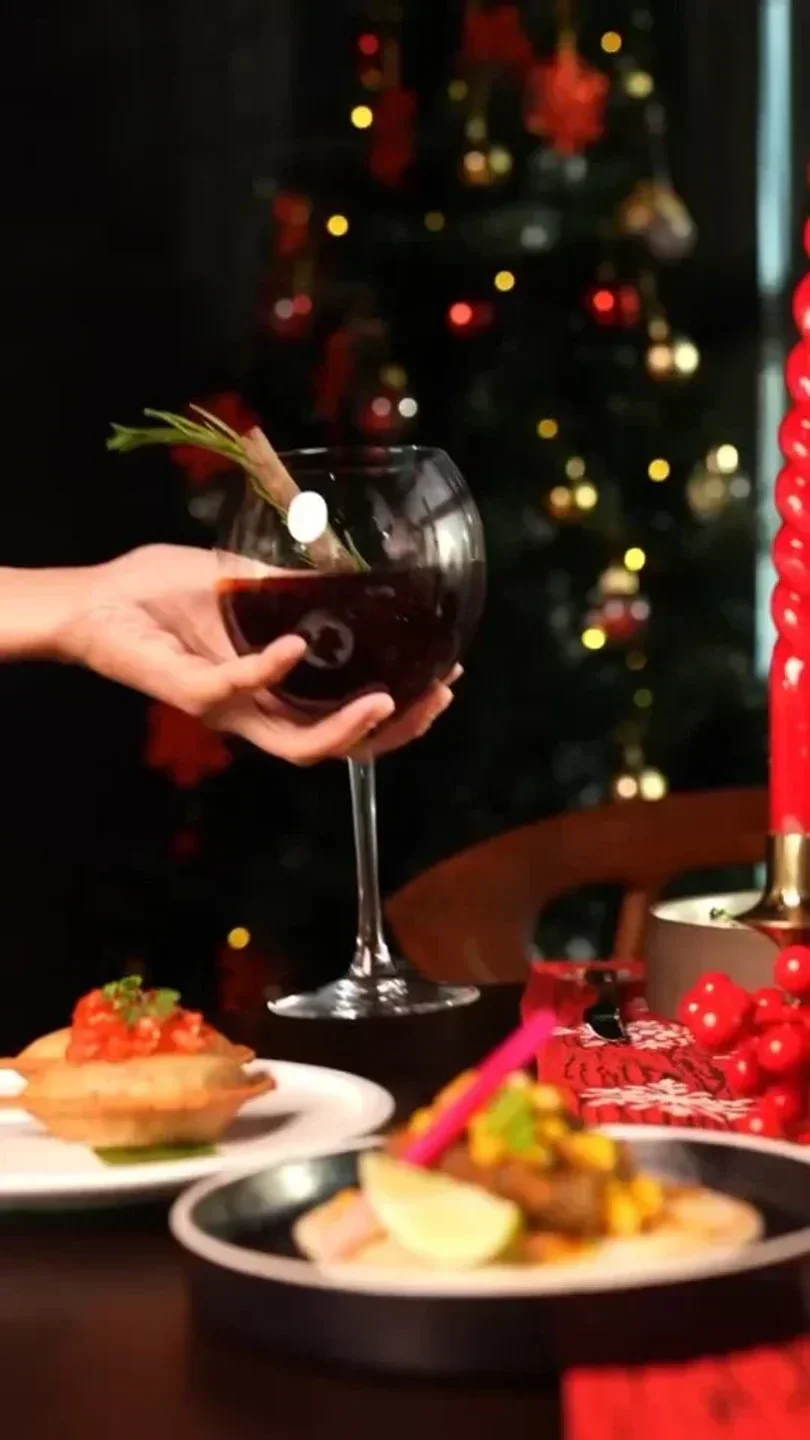 Mint Leaf Dubai: A hand holding a red wine glass with food and festive decor