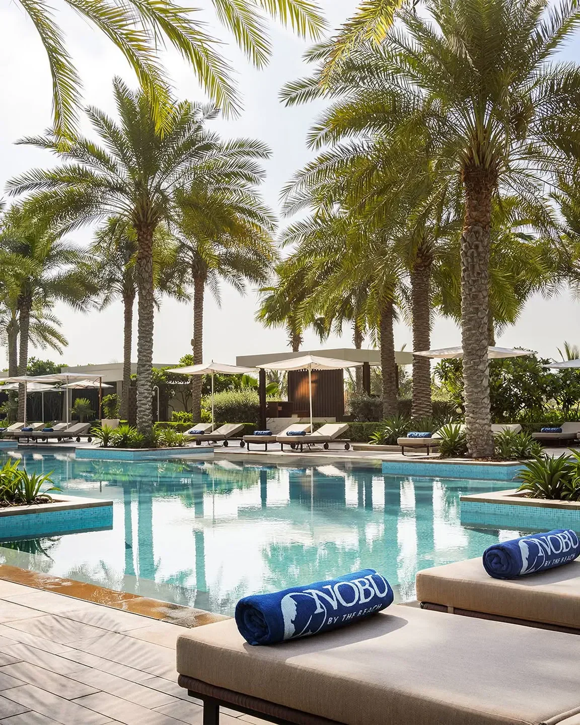 Relaxing pool at Nobu By The Beach in Dubai, surrounded by palm trees and luxury.
