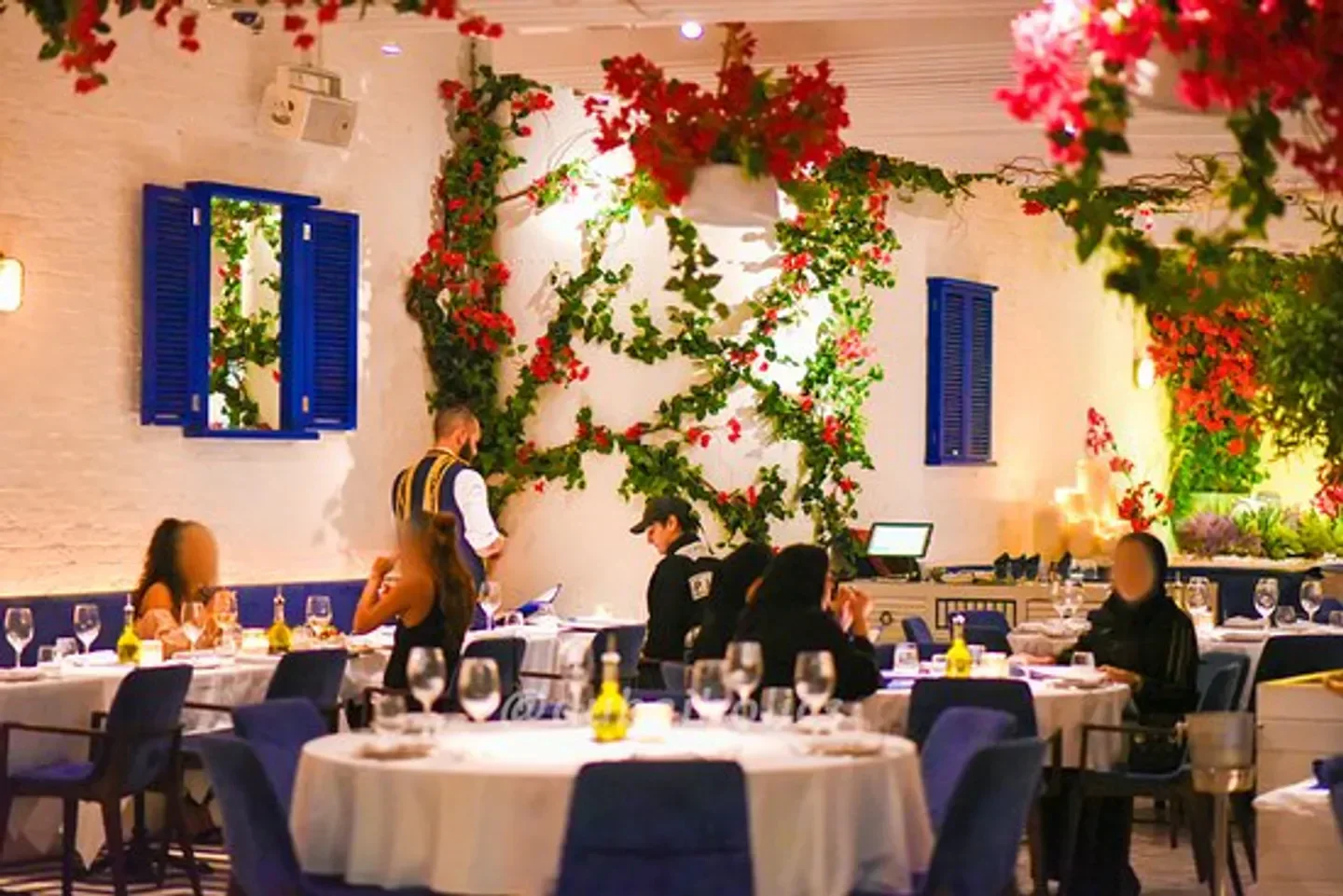 Interior of Opa restaurant in Dubai with floral decor and dining guests.