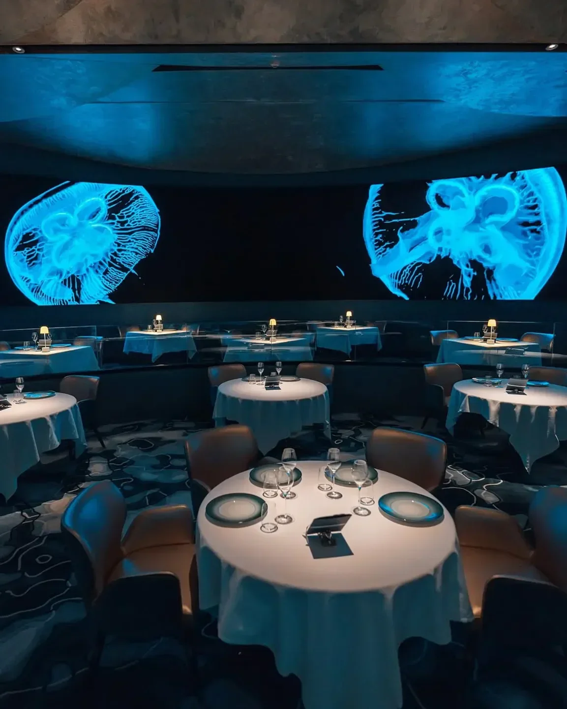 Ossiano Dubai restaurant's unique interior with jellyfish projections, elegant tables, and chairs.