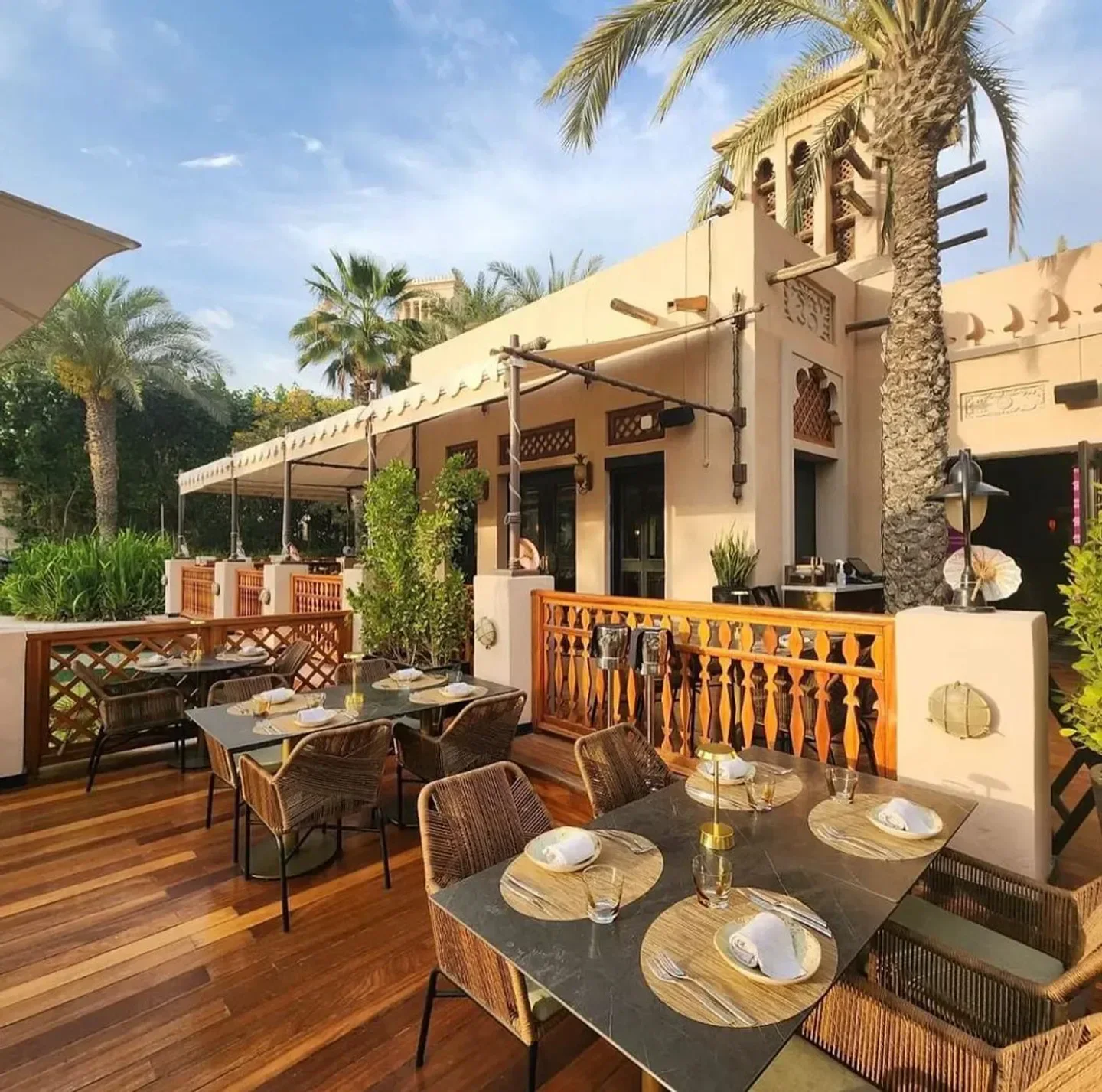 Outdoor dining at Pai Thai in Dubai, featuring elegant tables and palm trees.