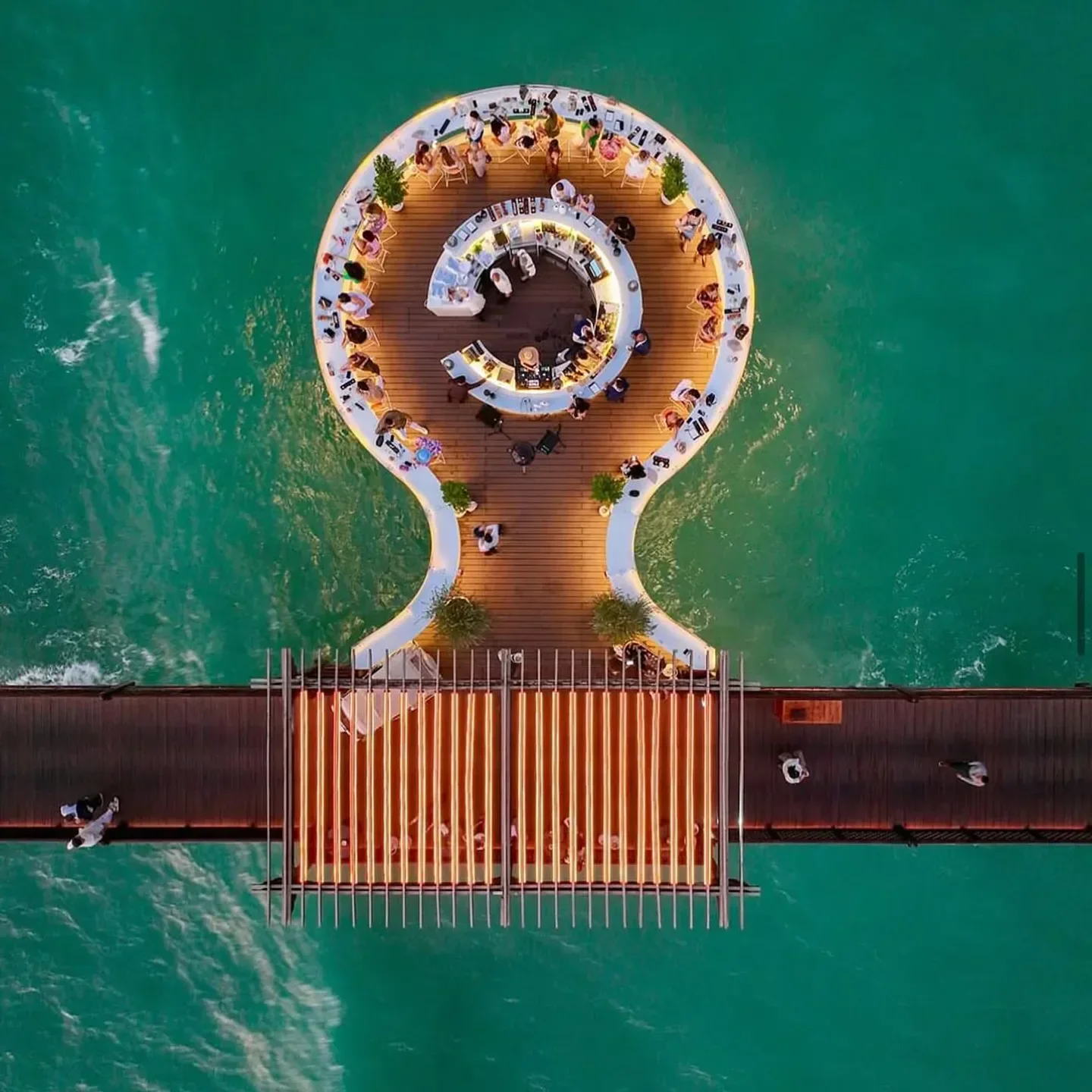 Aerial view of Pierchic restaurant in Dubai, over turquoise water with diners.
