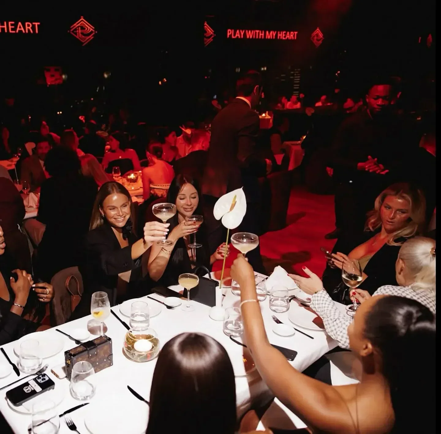 Group toasting at Play restaurant Dubai, enjoying cocktails and a vibrant atmosphere.