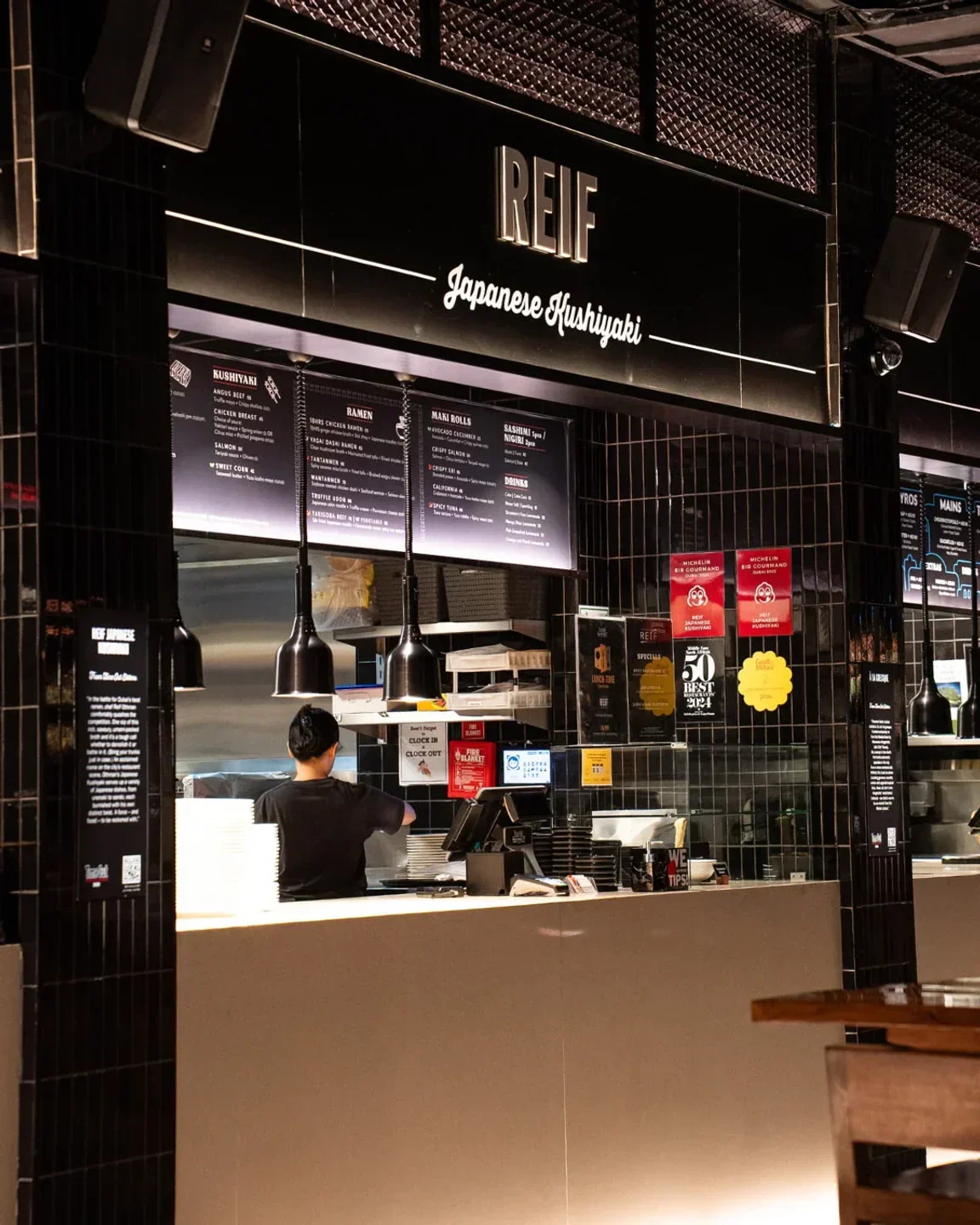 Interior view of Reif Kushiyaki in Dubai, featuring the restaurant's signage and kitchen.