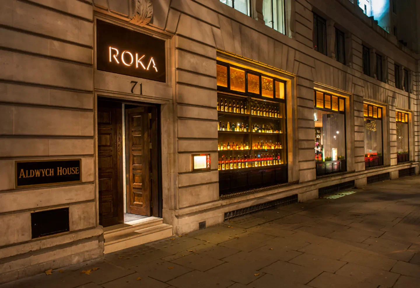 Roka Dubai restaurant exterior at night, featuring lit signage and open entrance.