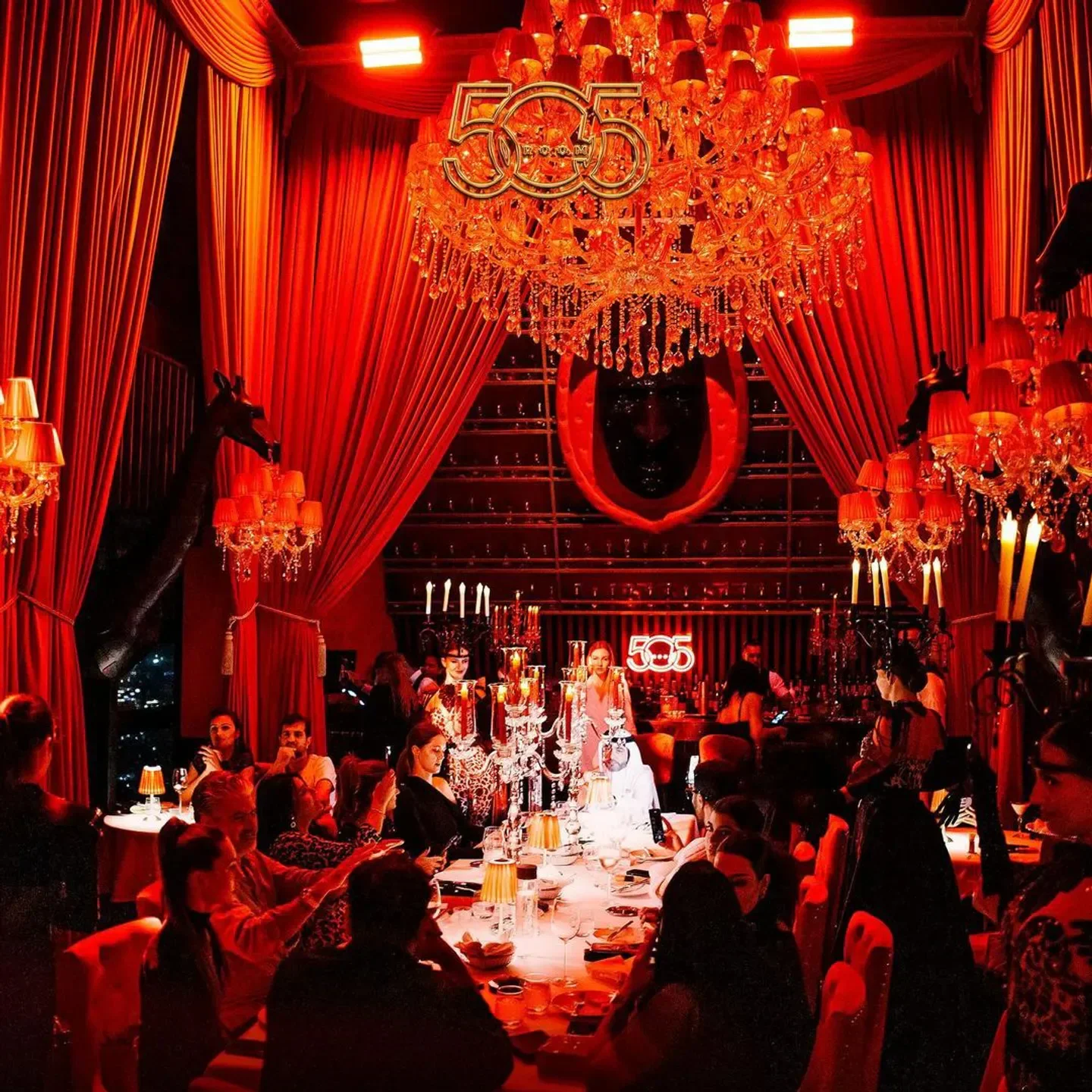 Elegant dining at Room 505 restaurant in Dubai, featuring crystal chandeliers and a red interior.