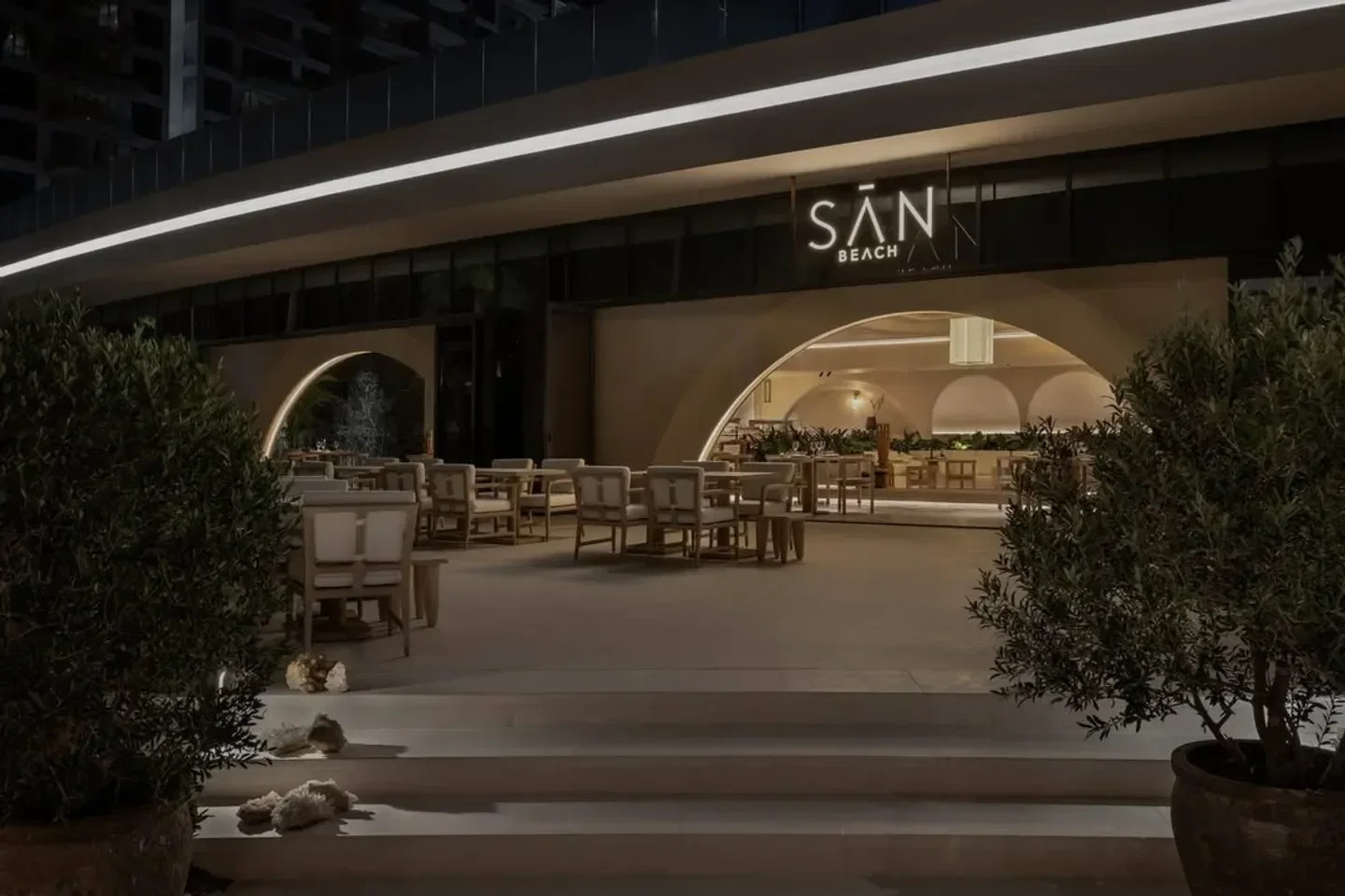 Entrance to San Beach, a stylish beach club in Dubai, with outdoor seating at night.