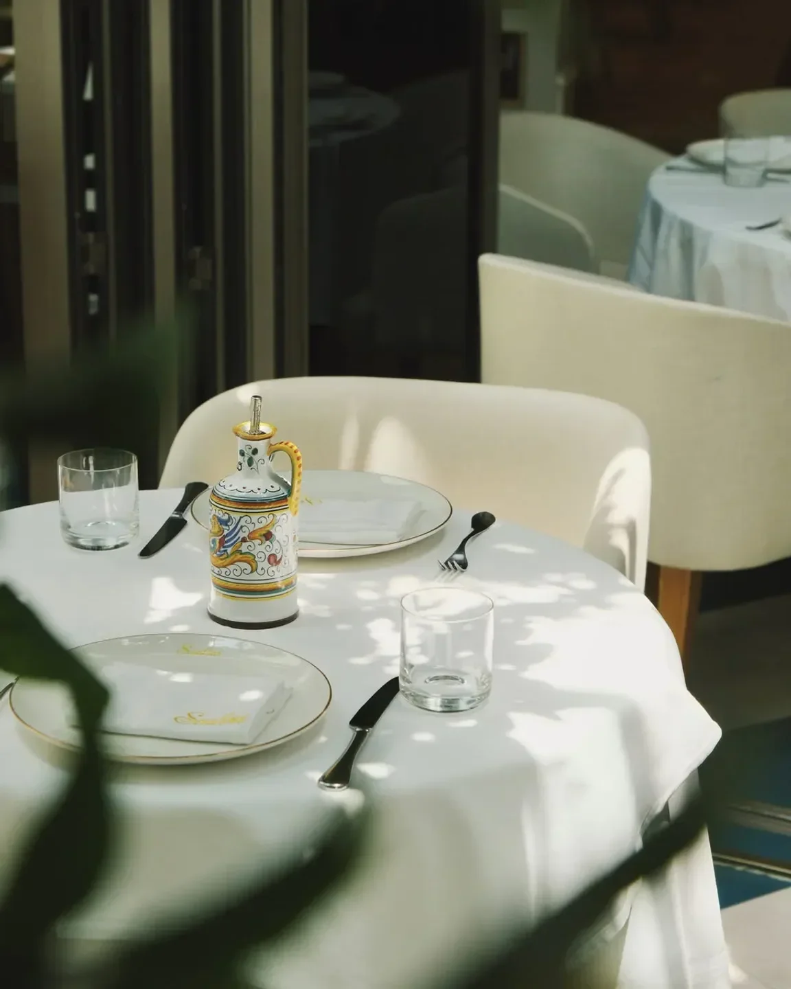 Elegant table setting at Scalini Dubai restaurant, featuring plates and decorative bottle.