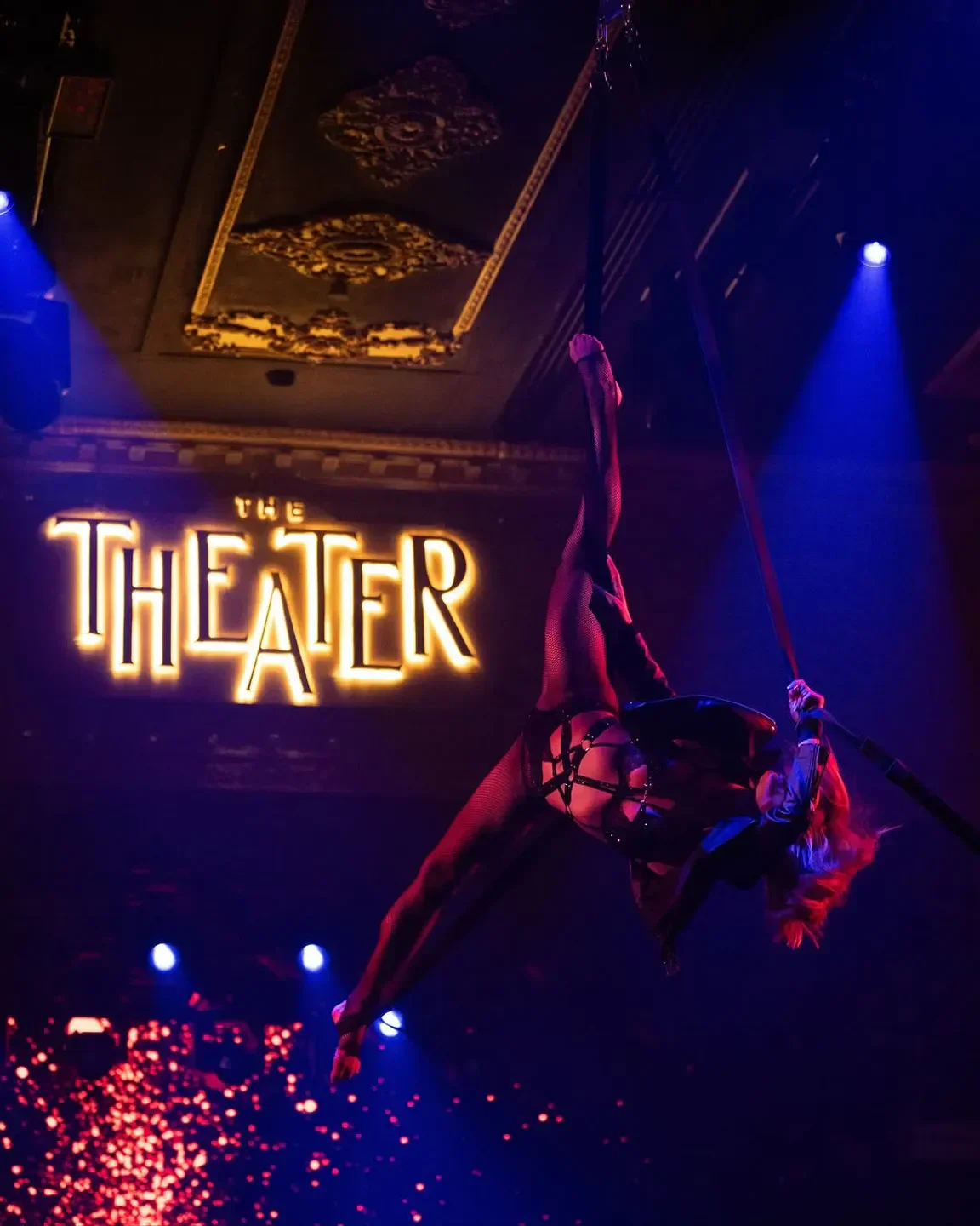 Aerial acrobatics performance at The Theater in Dubai, illuminated by dramatic lighting.