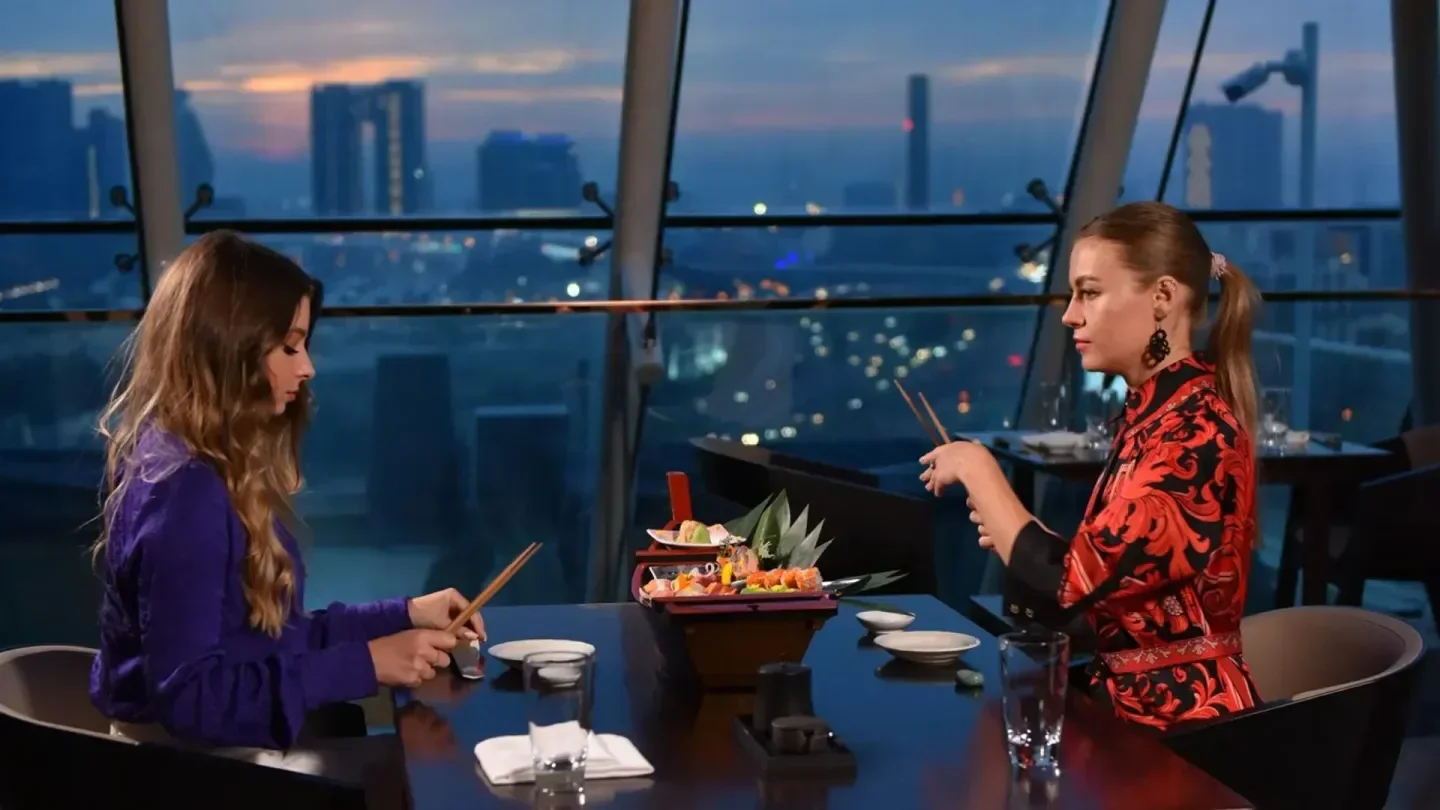 Diners enjoying sushi at Tomo restaurant in Dubai with a stunning city view at dusk