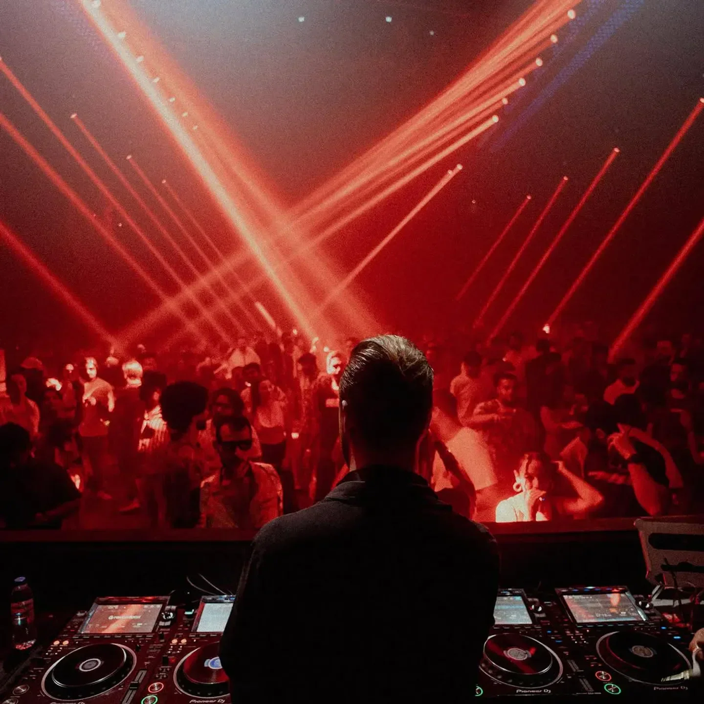 DJ at Yume Dubai nightclub, red laser beams illuminating the crowd and music decks.
